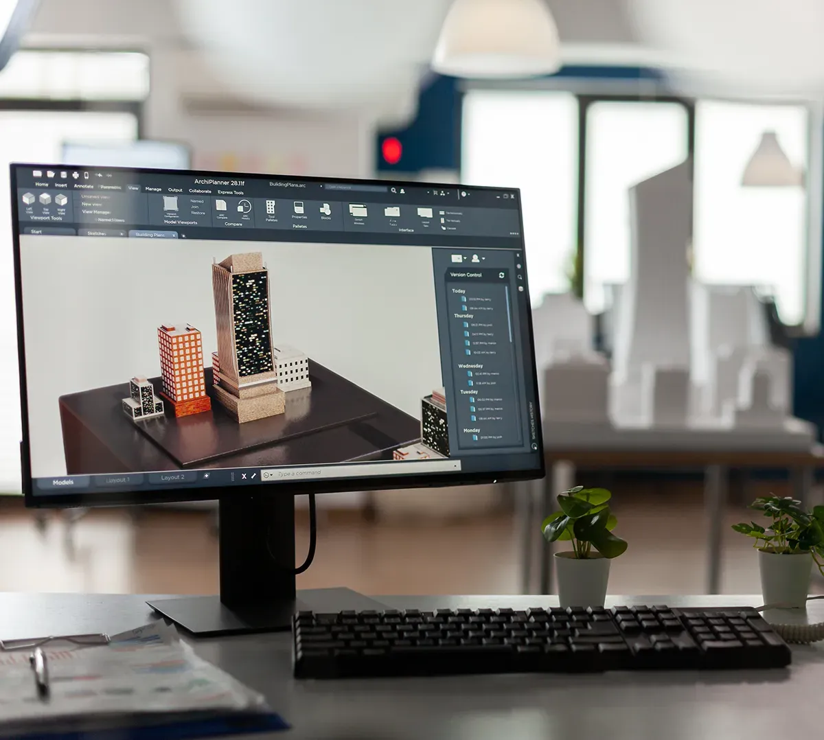 Computer workstation displaying 3D server models on a monitor in a modern office environment.